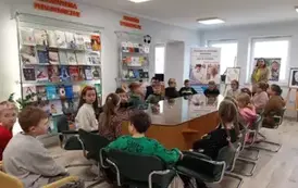 Uczniowie siedzą w bibliotece na tle ekspozycji książek