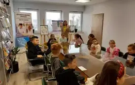 Uczniowie siedzą przy szklanym stole w czytelni