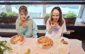 Dziewczynki kosztują wykonaną przez siebie pizzę