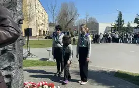 Harcerze z opiekunem składają kwiaty pod pomnikiem