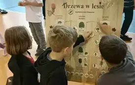 Uczniowie przy planszy edukacyjnej Nadleśnictwa