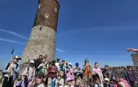 Uczestnicy wycieczki na tle zamkowej wieży