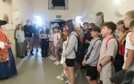 Grupa uczni&oacute;w słuchająca przewodniczki w Twierdzy w Kłodzku