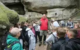 Grupa uczni&oacute;w słuchająca przewodnika w drodze na Szczeliniec