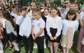 Grupa uczni&oacute;w klas młodszych z wychowawczynią, za nimi rodzice