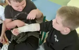 Dw&oacute;ch chłopc&oacute;w bandażuje rękę