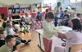 Uczniowie obserwują jak jedna z uczennic bandażuje rękę pielęgniarce