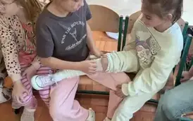 Dwie dziewczynki bandażuje nogę