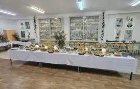 Pięknie udekorowany i zastawiony st&oacute;ł w jadalni szkolnej na tle gablot z pucharami za osiągnięcia sportowe