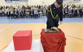 Przedstawiciel Państwowej Straży pożarnej  podczas umieszczania symbolicznej tarczy na tabliczce pamiątkowej