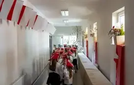 Uczniowie  w czerwonych biretach czekają na wejście na uroczystość