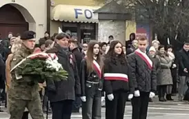 Uczniowie z dyrektorem składają kwiaty pod pomnikiem
