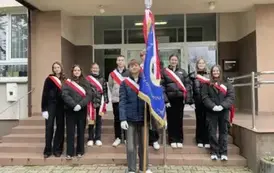 Grupa uczni&oacute;w ze sztandarem biorących udział w 107 rocznicy Odzyskania Niepodległości