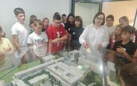 Grupa uczni&oacute;w na tle makiety Sejmu Rzeczypospolitej Polskiej w Warszawie  znajdującym się w Gmachu Sejmu