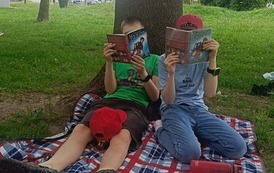 Dwaj uczniowie czytają Czerwone krzesło w parku miejskim
