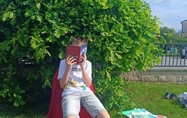 Uczeń klasy 4B na czerwonym krześle czyta lekturę
