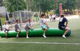 Uczniowie na pompowanej belce pr&oacute;bują dotrzeć do mety