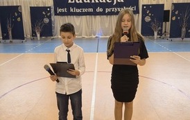 Dwoje uczni&oacute;w klas piątych na scenie wita gości