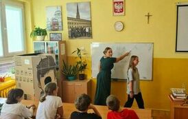 Sala lekcyjna, nauczycielka przy tablicy, uczniowie siedzący w ławkach