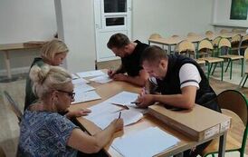 Dwie kobiety i dw&oacute;ch mężczyzn wypełniający dokumenty