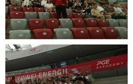 Uczniowie siedzą na trybunach i słuchają jak Pani przewodnik opowiada historię Stadionu Narodowego