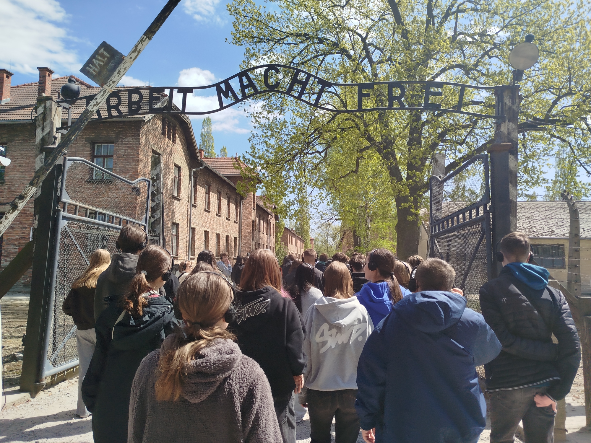 Grupa uczni&oacute;w przechodzi przez bramę Państwowego Muzeum Auschwitz-Birkenau w&nbsp;Oświęcimiu