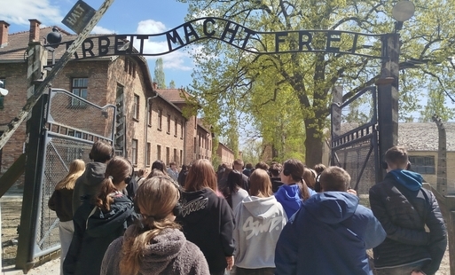 Grupa uczniów przechodzi przez bramę Państwowego Muzeum Auschwitz-Birkenau w Oświęcimiu