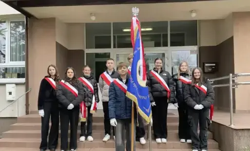 Grupa uczniów ze sztandarem biorących udział w 107 rocznicy Odzyskania Niepodległości